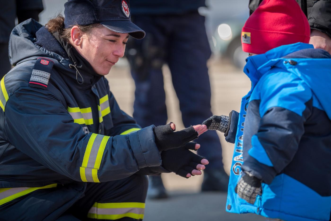 A woman firefighter greets a young refugee child from Ukraine as he arrives at the Vama Siret border crossing, Romania. The Vama Siret border crossing connects northeast Romania with Ukraine. Located north of Siret and further in the south the city of Suceava, the crossing connects Romania with the Ukrainian village of Terebleche and further north the city of Chernivtsi. Following the invasion of Ukraine by Russian military starting on 24 February 2022, close to half a million refugees have fled across the 