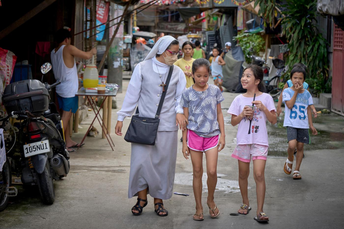 Nun walks with children in a poor neighborhood