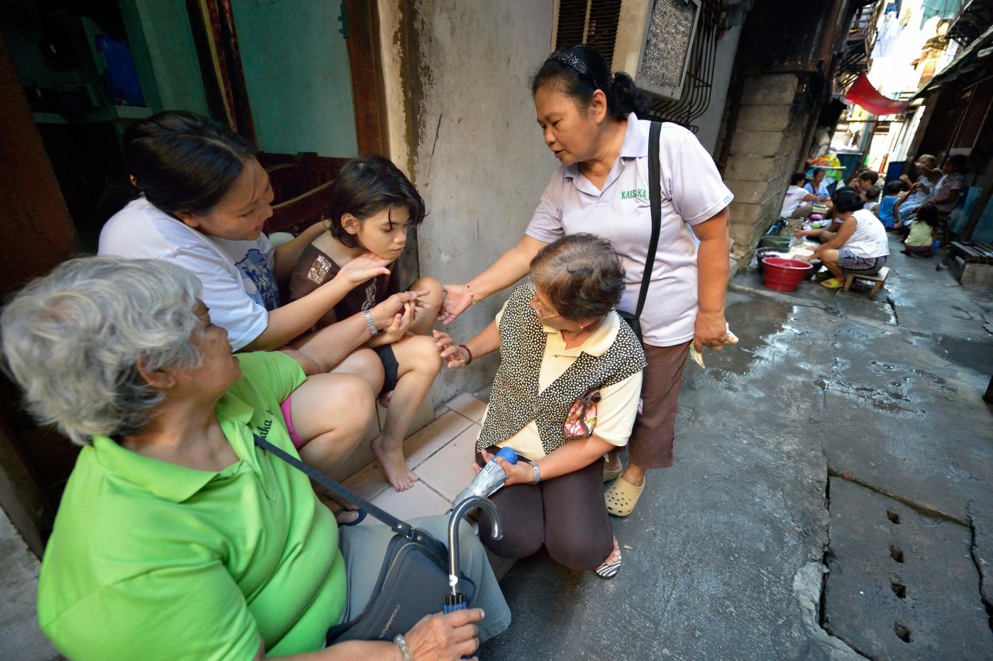 Eileen Peralta and her 12-year old daughter Erin, who has autism, sit on the step of their home in the Malate neighborhood of Manila. They're being visited by other members of Kaisahan ng Magulang at Anak na Maykapansanan (Kaisaka), a mothers' group that carries out community based rehabilitation with families which have members with disabilities.