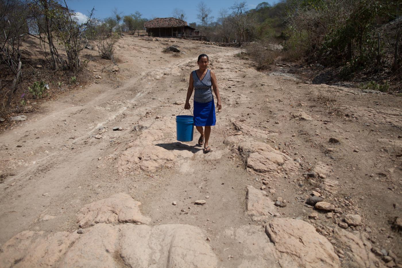 A woman carries a bucket to fill at a village well.