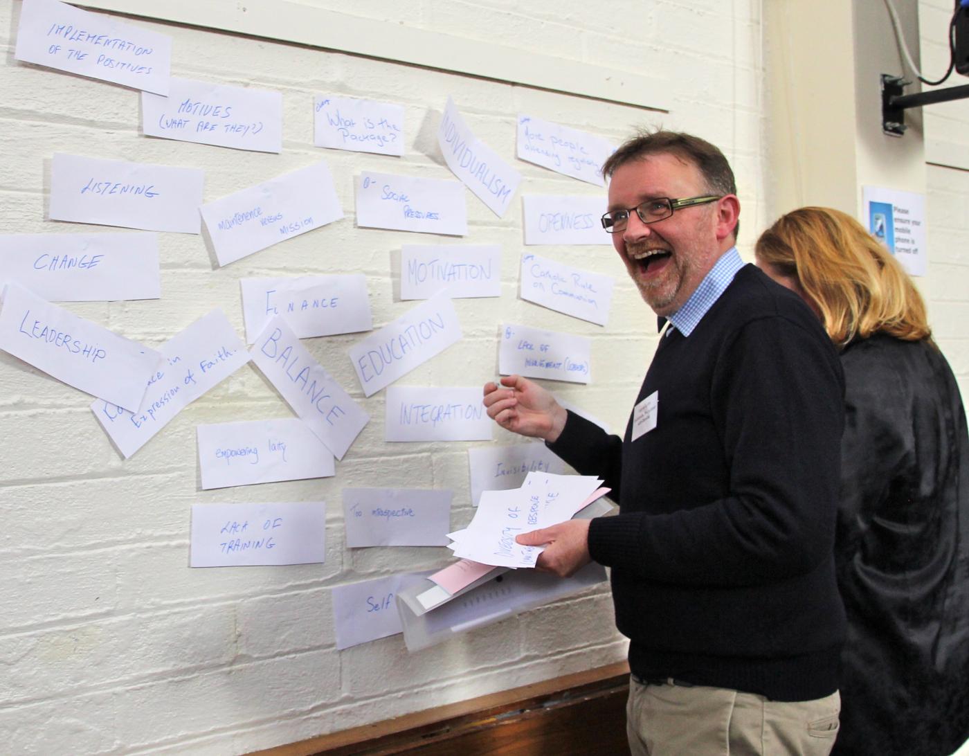 Rev. Eugene Griffin has a moment of joy at a collage wall during a "Come&C" day in Dublin and Glendalough, Ireland. © Lynn Glanville