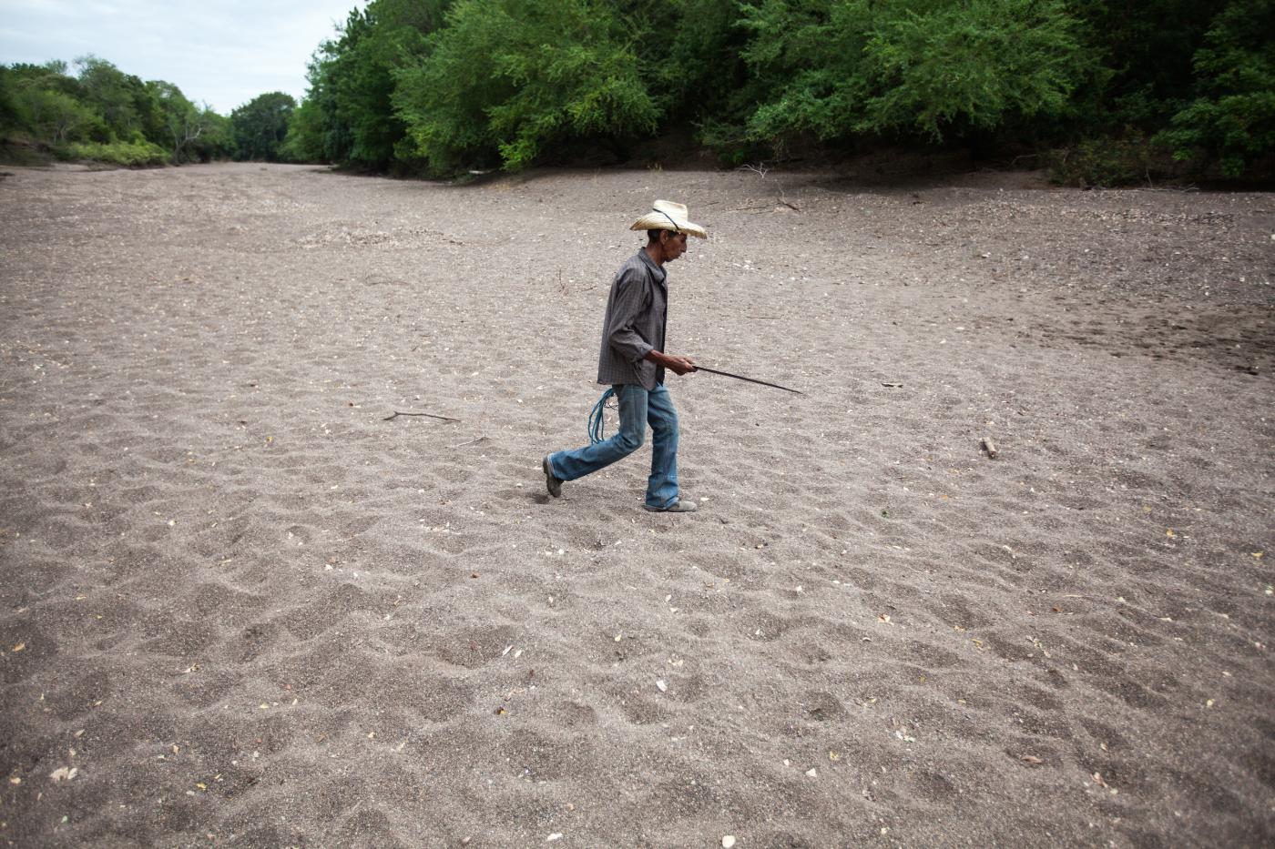 “Las comunidades más pobres son las más afectadas por el cambio climático”. En esta imagen, un criador de ganado camina por el lecho de un río seco. © Sean Hawkey/CMI