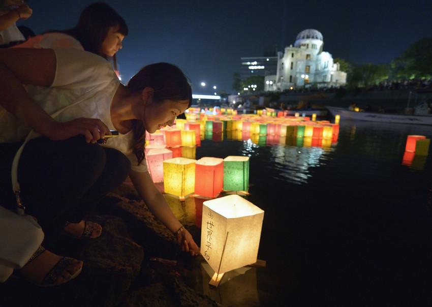 A woman sets a floating candle lantern on the river in Hiroshima on August 6, 2015. Photo: Paul Jeffrey/WCC, 2015.