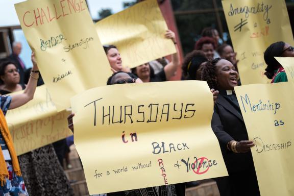 Women marching with Thursdays in Black placards