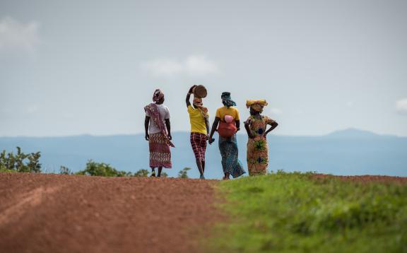 Women walk on countryside gravel road on a cloudy day. 