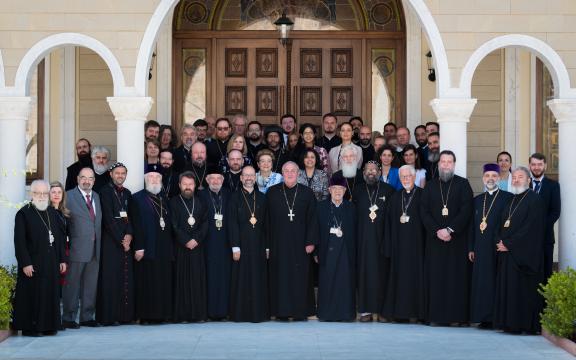 People posing for a group photo, many of them wearing black religious garb. 