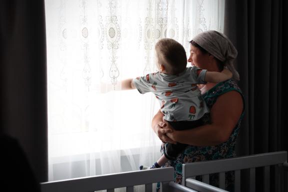 Woman holds a child looking out of the window