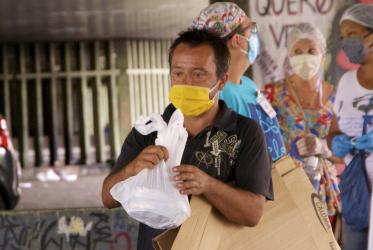 a Brazilian poor man carries a bag of food