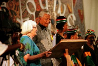 Nelson Mandela stands next to Pauline Webb at a conference podium. 