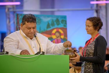 Tahiti holds ashes in his hand as he reads from scripture