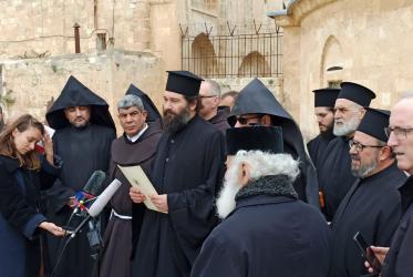 People in religious garb gathered outdoors in front of a set of microphones. 