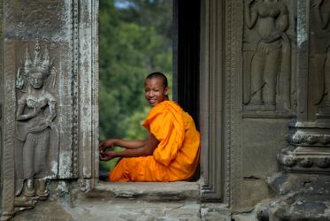 A Buddhist monk sits in the doorway of a temple in the Angkor Wat complex in Cambodia, which dates to the 12th Century, Photo: Paul Jeffrey/Life on Earth Pictures