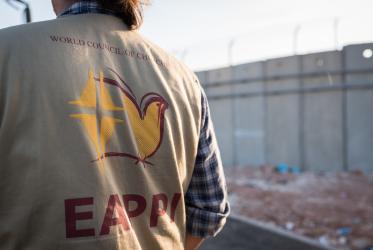Man seen from behind wearing a vest reading 'EAPPI'
