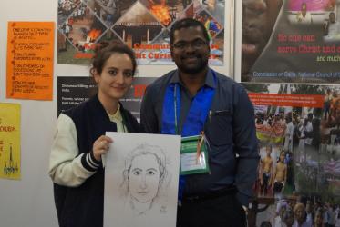 Rev. Sunil Raj Phillip (right) shows caricature of an assembly participant at the WCC assembly in Busan.