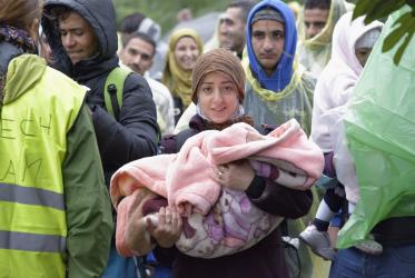 Eine Frau hält ein Baby in ihren Armen, als sich der Flüchtlingszug der kroatischen Grenze in der Nähe des serbischen Dorfes Berkasovo nähert. Foto: Paul Jeffrey/QCT